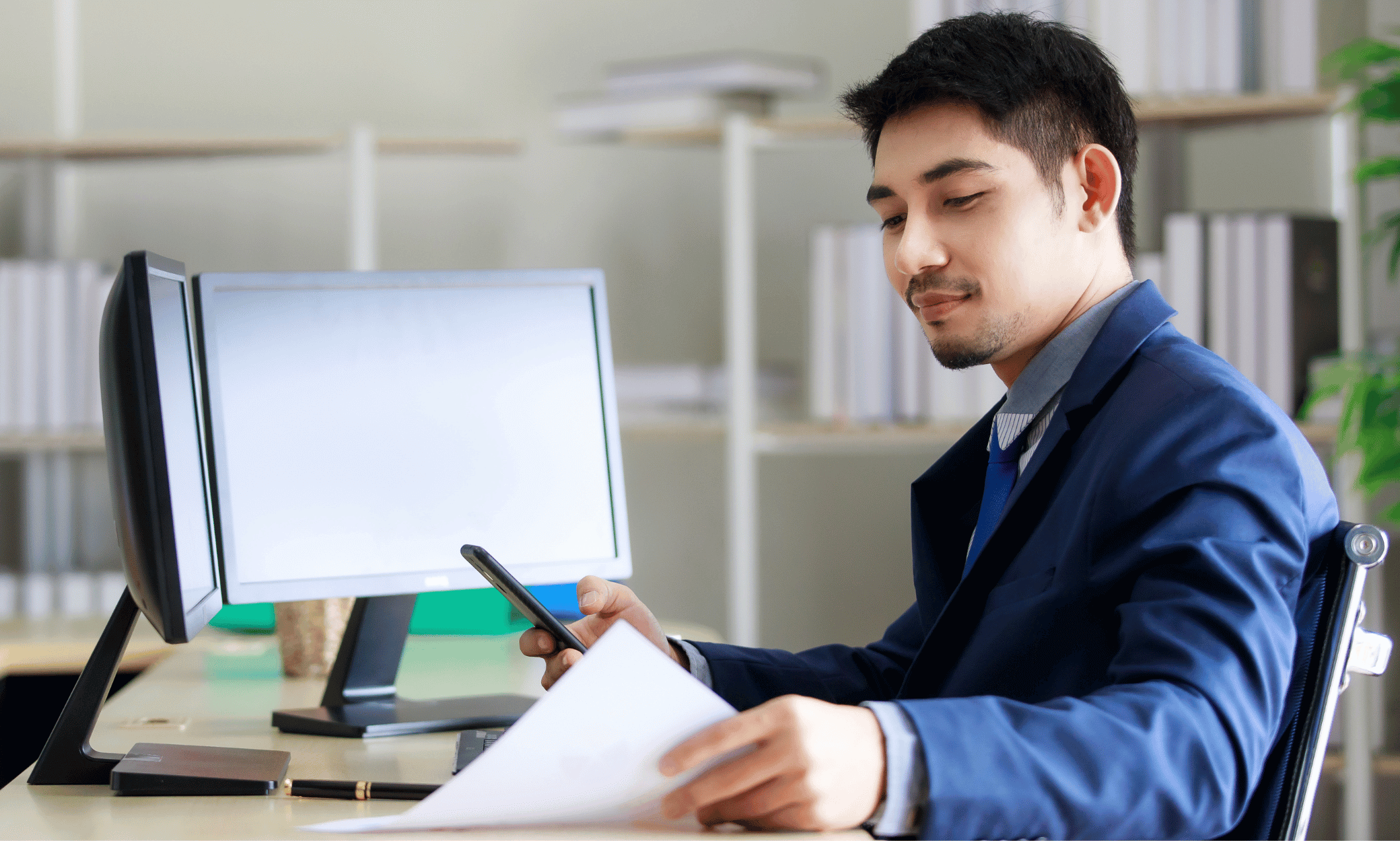 Someone looking at a piece of paper at their desk.