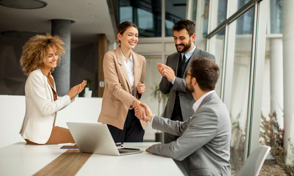 A group of people celebrating as two people shake hands.